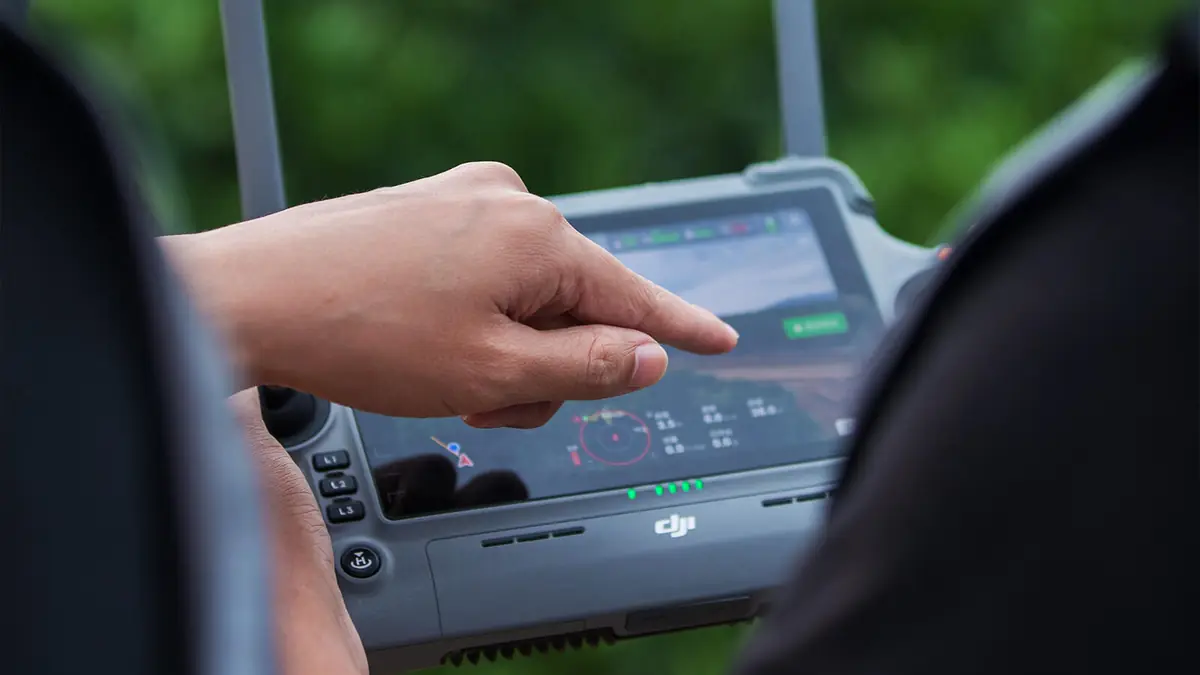 Instrutor aponta parâmetros de voo na tela do controle do drone agrícola DJI